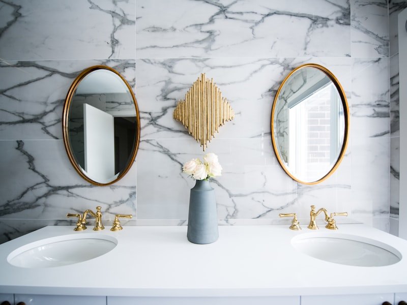Brass fixtures and round mirrors in a marble bathroom — Rockcliffe Park renovation.