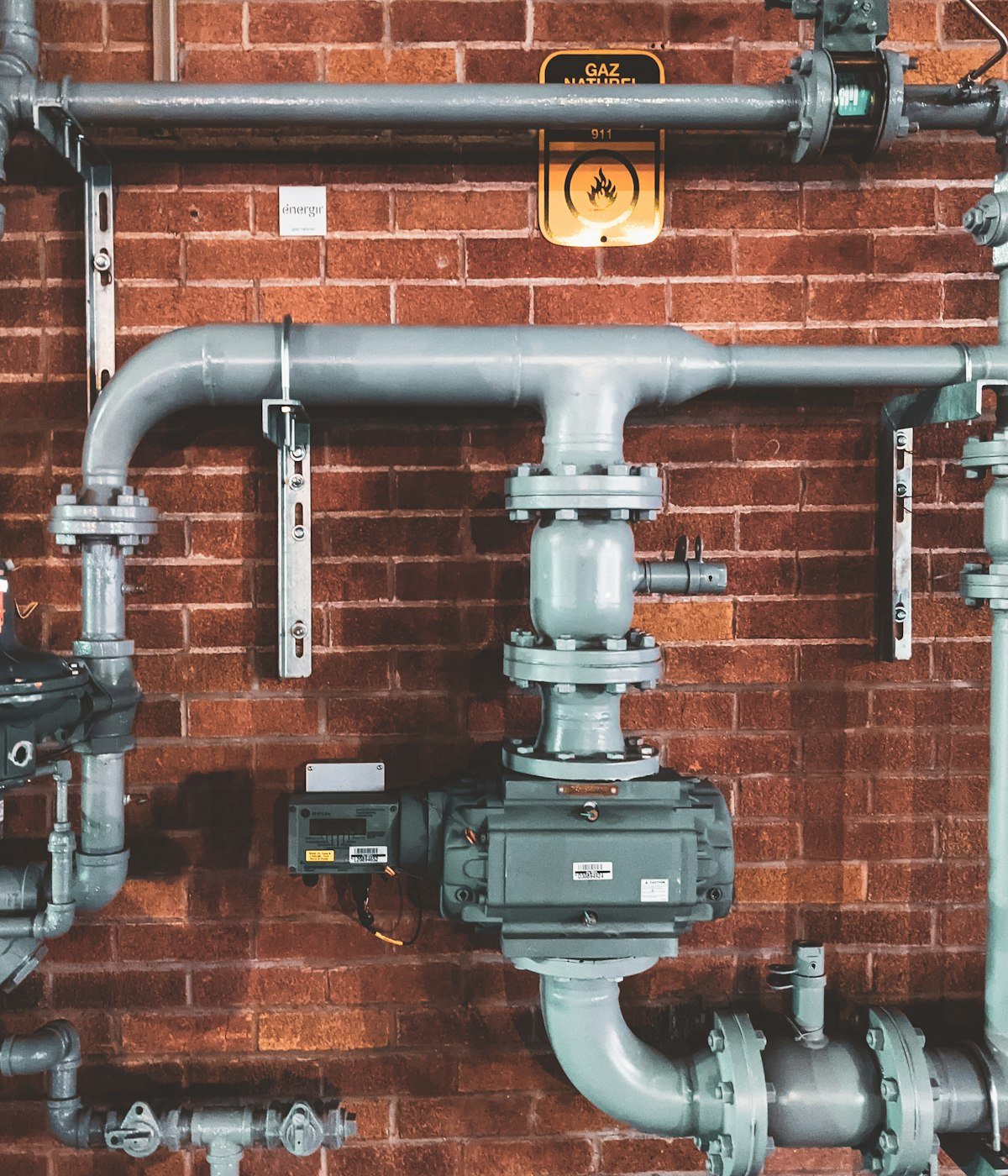 Industrial plumbing pipework on a brick wall — the kind of mechanical work licensed master plumbers in Ottawa handle every day.