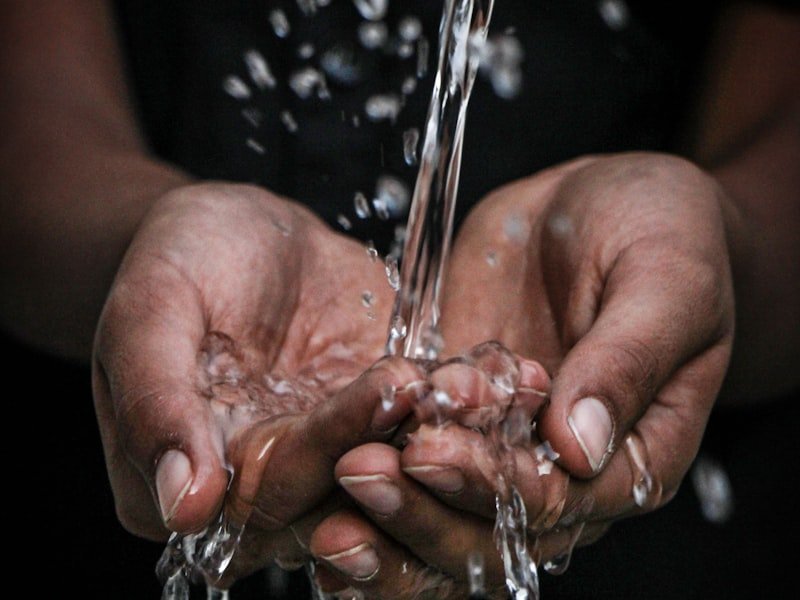 Cupped hands catching clean water — softener and water treatment installation.